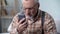 Old man looks incredulously at cellphone, new technology complicated for elderly