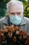 Old man in a medical mask with a bunch of dried wilted roses. The concept of withering, old age and disease. Close-up portrait