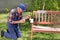 Old man painting bench in garden