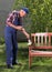 Old man painting bench in garden
