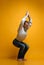 Old man practicing yoga doing stretching exercises against yellow background