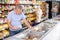 Old man purchaser choosing frozen fish in big supermarket