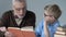 Old man reading book for grandson, helping with homework, spending time together