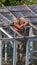 The old man repairs the greenhouse in the garden