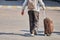 Old man with suitcase on wheels