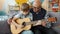 Old man teaching talented little grandson to play the guitar in apartment