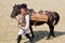 Old man in traditional costume with burden horse