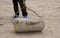 Old man uses stone roller to compress the flat roof of earth-s