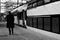 Old man walking along a train of an empty platform whom is travelling or said goodby to someone - BW