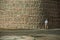 Old man walking in front of the thick city wall of Avila