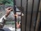 Old Man Welding a Corrosive Black Iron Handle of Gate