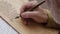 old man with white beard with medieval pen transcribes a manuscript in latin