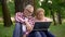 Old man and woman sitting on grass and watching thriller movie trailer on laptop