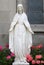 Old Marble Statue of Virgin Mary and Pink Geranium Flowers in Indiana