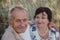 An old married couple on a summer walk in the field. In focus close up of the spouse`s face