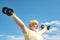 Old mature man exercising with dumbbell. Senior sportman exercising with lifting dumbbell on blue sky background