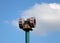 Old mechanical warning siren on a pole against a blue cloudy sky