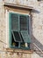 Old mediterranean window with green shutters