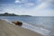 Old metal buoy laying on a sand beach,blue sky and mountain in background.