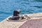 Old metal dock mooring pole with ring and rope for securing fishing boats