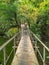 Old metal rusty footbridge over the river in the park.