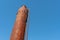 An old metal rusty water tower. Old production technology, processing, drying in the agro-industrial complex. Red silo on the sky