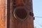 An old metal rusty water tower. Old production technology, processing, drying in the agro-industrial complex. Red silo on the sky