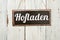 Old metal sign in front of a white wooden wall - German word for Farm Shop - Hofladen