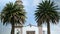 Old Mexican church entrance surrounded by bushes and two palm trees