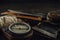 Old military compass, rusty hunting bushcraft knife, small axe and a linen rope on the dark wooden table.