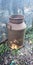 Old milk can in the garden still working as a fence holder next to a garden bed