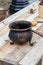 Old mini bowler on a three-legged cast-iron pot stands on a wooden table, traditional kitchenware