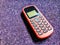 Old Mobile Phone with Texting or SMS Button Keyboard or Keypad on Sparkling Purple Fabric Background