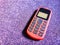 Old Mobile Phone with Texting or SMS Button Keyboard or Keypad on Sparkling Purple Fabric Background