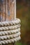 Old mooring rope wrapped on a wooden pole while holding the moored vessel