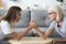 Old mother and grown daughter arm wrestling having family fight