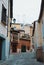Old narrow medieval street of Toledo, vintage houses with lanterns and pots with plants on the terrace and a wall covered with dr