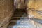 Old narrow stone staircase leading to stone bricks wall with closed window