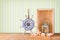 Old nautical wood wheel, anchor and shells on wooden table over retro background