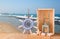 Old nautical wood wheel, anchor and shells on wooden table over sea background