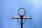Old neglect basketball backboard with rusty hoop above street court. Blue sky