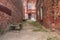 Old neglected quarter, walls of red brick destroyed form a perspective to the front door of a residential building