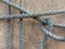 Old nylon ship ropes tied to knot bound around cement electrical post on ground flooring closeup.