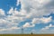 Old oil and gas rig profiled on blue sky with white clouds, in spring