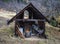 Old open front wooden shed with an generator and tools and piled wood in rural setting with trees behind