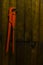 Old orange pipe wrench hanging on wooden wall