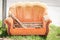 Old orange sofa thrown in the garbage from home on the street