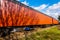 Old orange steal railroad car on tracks with a rusted bottom.