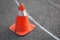 Old orange striped cone on road.