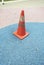 Old orange traffic cone on the colourful surface of playground